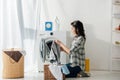 woman in grey shirt and jeans putting clothes in basket near washer Royalty Free Stock Photo