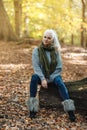 Woman in grey sweeter and jeans sitting in Autumn park