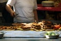 Woman grilling burgers and meat on grill at traditional outdoor festival