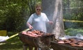 Woman grills burgers and hot dogs in a bacjkyard cookout