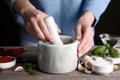 Woman grinding coriander at wooden table, closeup