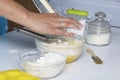 The woman grinds the butter and adds to the dough. Next container with flour and coconut shaving.