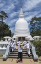 Woman and group of children in uniform on the stairs at white buddhist stupa building located in Nuwara Eliya town