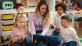 Woman and group of kids having lesson using touchpad at kindergarten Royalty Free Stock Photo