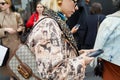 Woman with Gucci bag and brown coat with comics design looking at smartphone before Gucci