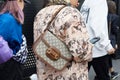 Woman with Gucci bag and brown coat with comics design looking at smartphone before Gucci