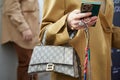 Woman with Gucci Balenciaga bag looking at smartphone with green cover before Genny fashion show