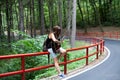 Woman with a guitar and backpack in a road trip with forest view