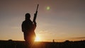 Silhouette of a woman with a rifle. A sieve in the field at sunset. Sports shooting concept. Back view Royalty Free Stock Photo