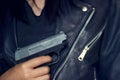 Woman with gun in hand on the black jacket texture background Royalty Free Stock Photo