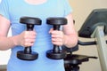 Woman in the gym holds a metal dumbbells. Sports equipment for increasing muscle mass