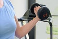 Woman in the gym holds a metal dumbbells. Sports equipment for increasing muscle mass