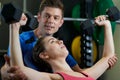 Woman In Gym Lifting Weights Encouraged By Personal Trainer