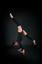 Woman gymnast showing athletic skill against dark background