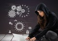 Woman hacker using a laptop in front of purple background with digital icons Royalty Free Stock Photo