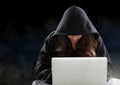 Woman hacker working on laptop in front of black background Royalty Free Stock Photo