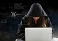 Woman hacker working on laptop in front of black digital background Royalty Free Stock Photo