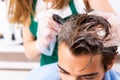 The woman hairdresser applying dye to man hair