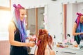 Woman hairdresser weaves to girl ginger dreadlocks.