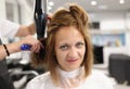 Woman hairdresser dries and straightens client hair with comb and hair dryer in beauty salon Royalty Free Stock Photo