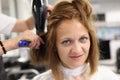 Woman hairdresser dries and straightens client hair with comb and hair dryer in beauty salon Royalty Free Stock Photo