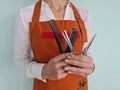 Woman hairdresser holds set of combs and scissors in barbershop