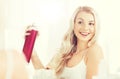 Woman with hairspray styling her hair at bathroom