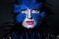 Woman with Halloween makeup. Model face bird character with blue and black feathers Royalty Free Stock Photo