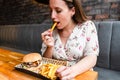 Woman hamburger eat. Hungry Caucasian Female Eating Tasty Burger. Fast food, people and unhealthy eating concept.