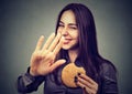 Woman with hamburger rejecting advise on healthy eating