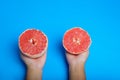 Woman han holding a cut pink grapefruit isolated on blue background. Royalty Free Stock Photo