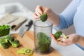 Woman hand adding broccoli to measuring cup