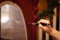 Woman hand aging hand carved ornaments of antique massive wooden cupboard door in pink color. Giving new life to old