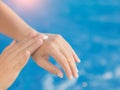 Woman hand apply sunscreen / sunblock by the swimming pool.