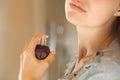 Woman hand applying fragrance on neck in the bathroom