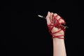 Woman hand with black pen tied with red rope, depicting the idea of freedom of the press or expression on dark background in low