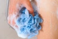 Woman hand with blue foamy sponge washing her body