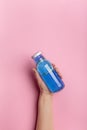 Woman hand with blue isotonic or detox drink on pink