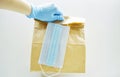 Woman hand in blue latex gloves holding craft disposable paper bag for delivery Royalty Free Stock Photo