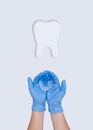 Woman hand in blue medical gloves holding silicone mouth guard with paper cut molar tooth. Tooth symbol sign. Orthodontic therapy Royalty Free Stock Photo