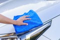 Woman hand with blue microfiber cloth cleaning the car