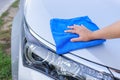 Woman hand with blue microfiber cloth cleaning the car