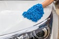 Woman hand with blue microfiber fabric washing headlight modern car or cleaning automobile.