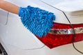 Woman hand with blue microfiber fabric washing taillight modern car or cleaning automobile. Royalty Free Stock Photo