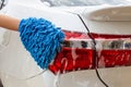 Woman hand with blue microfiber fabric washing taillight modern car or cleaning automobile. Royalty Free Stock Photo