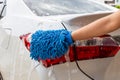 Woman hand with blue microfiber fabric washing taillight modern car or cleaning automobile. Royalty Free Stock Photo