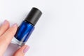 Woman hand with blue nail polish bottle on white background Royalty Free Stock Photo