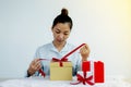 Woman hand in a blue shirt opening a gold gift box tied with a red ribbon present for the festival of giving special holidays like Royalty Free Stock Photo