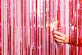 Woman hand  breaking through a pink tinsel with a burning sarkler Royalty Free Stock Photo