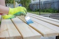 Woman Hand with a brush varnishes old wooden boards. Worker paint with brush a wood wall from boards in construction site